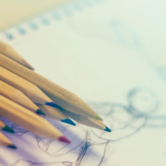 des crayons de couleur posés sur un dessin crayonné